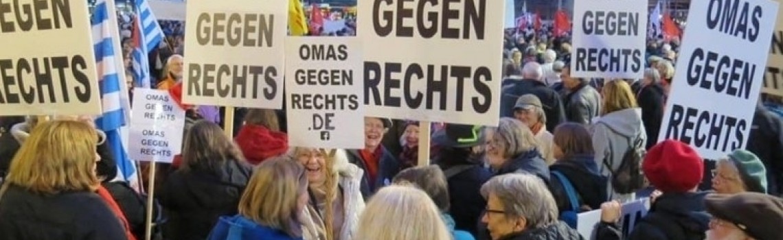 Eine Gruppe von Menschen auf einer Demo. Sie halten Schilder in die Höhe.