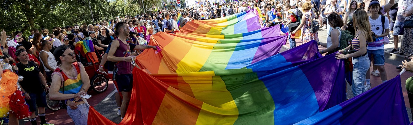 Eine Menschengruppe, die eine riesige Regenbogenflagge in ihrer Mitte ausgebreitet hat (© Stadt Frankfurt, Katarina Ivanisevic)