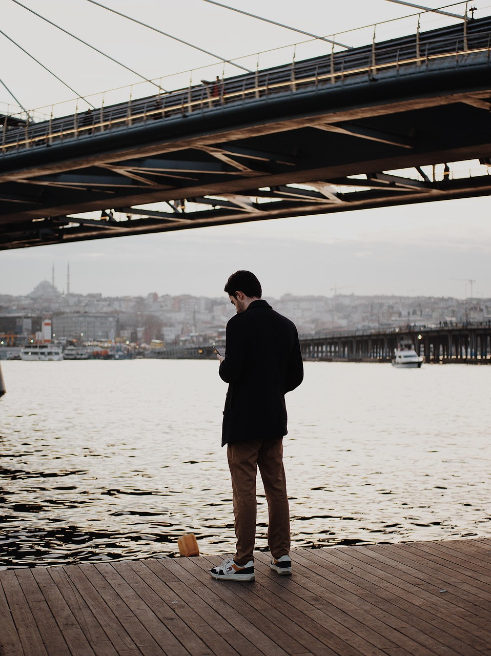 Ein Man mit Handy unter einrer Brücke