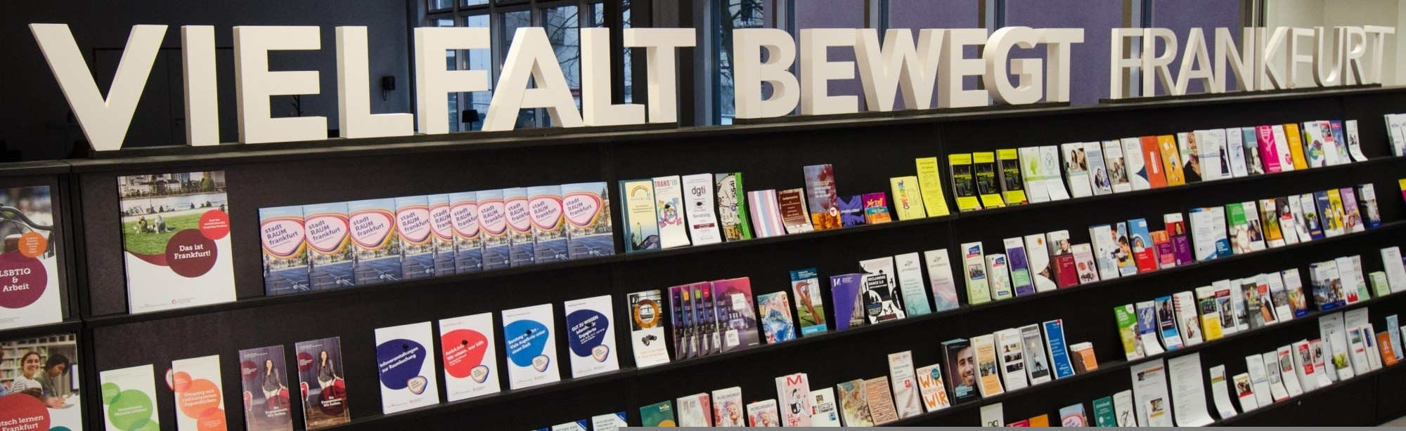 Flyerwand im Frankfurt Welcome & Information Center mit dem Schriftzug "Vielfalt bewegt Frankfurt"