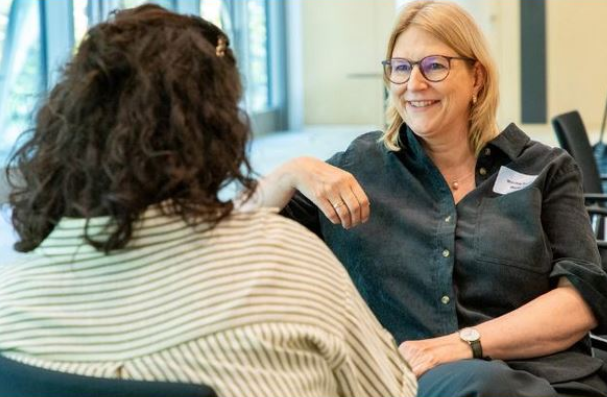Zwei Frauen gegenübersitzend lächelnd im Gespräch
