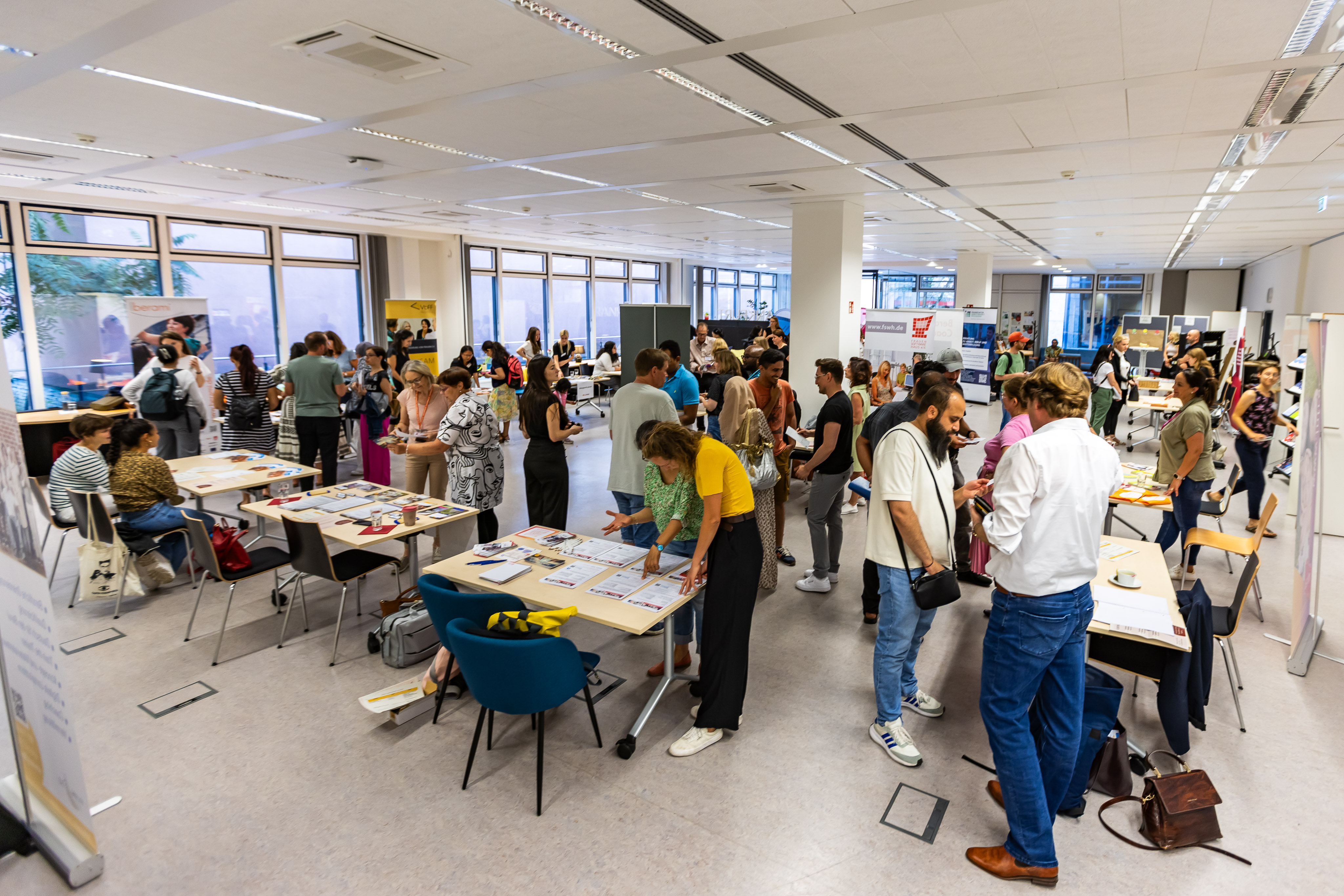 Mehrere Menschen stehen in Gruppen an Infotischen im Frankfurt Welcome & Information Center..