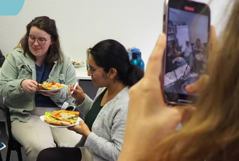 Zwei Frauen beim Essen, die mit einem Handy gefilmt werden