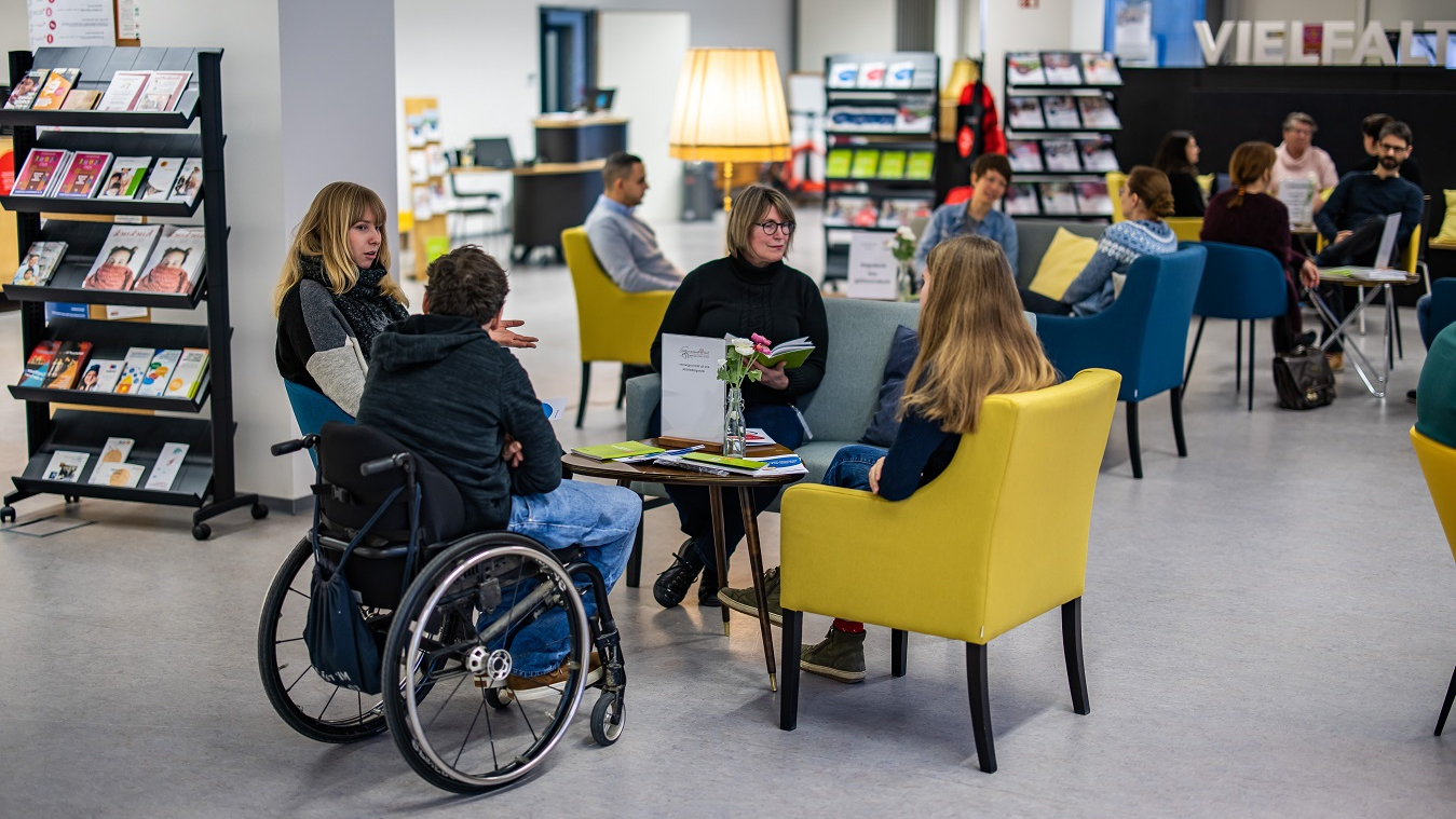 Vier Personen sitzen im Gespräch rund um einen Tisch