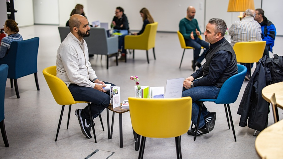 Zwei Männer sitzend um einen Tisch bei einem Beratungsgespräch