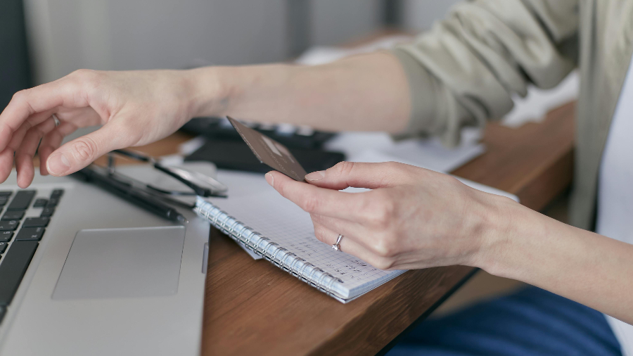 Ausschnitt einer Person mit Chipkarte vor einem Laptop