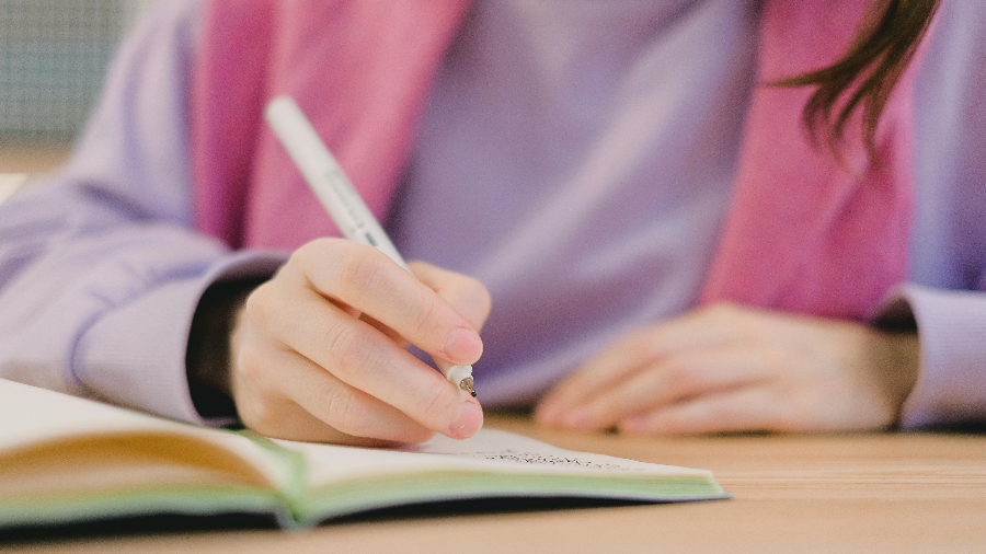 Bildausschnit eines Jugendlichen schreibend auf einem Block