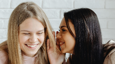 Eine Frau flüstert eier anderen Frau etwas ins Ohr