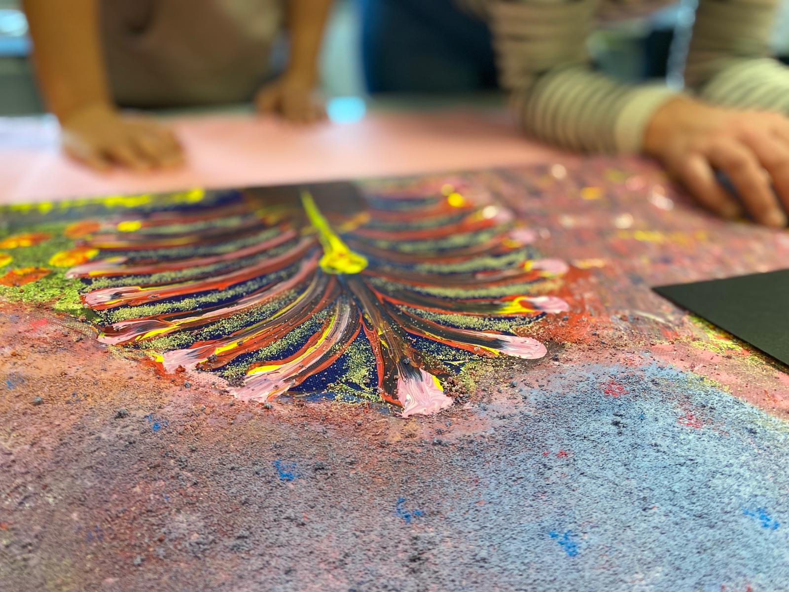 Ein Kunstwerk auf einem Tisch, während sich Leute darüber beugen.