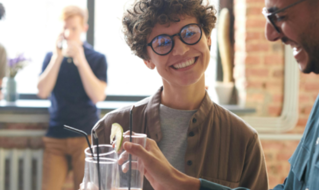 Eine Frau und ein Mann lachend im Gespräch mit Gläsern in der Hand