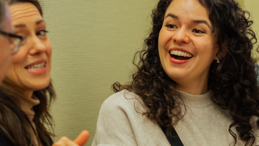 Zwei Frauen lächelnd im Gespräch mit weiteren Personen