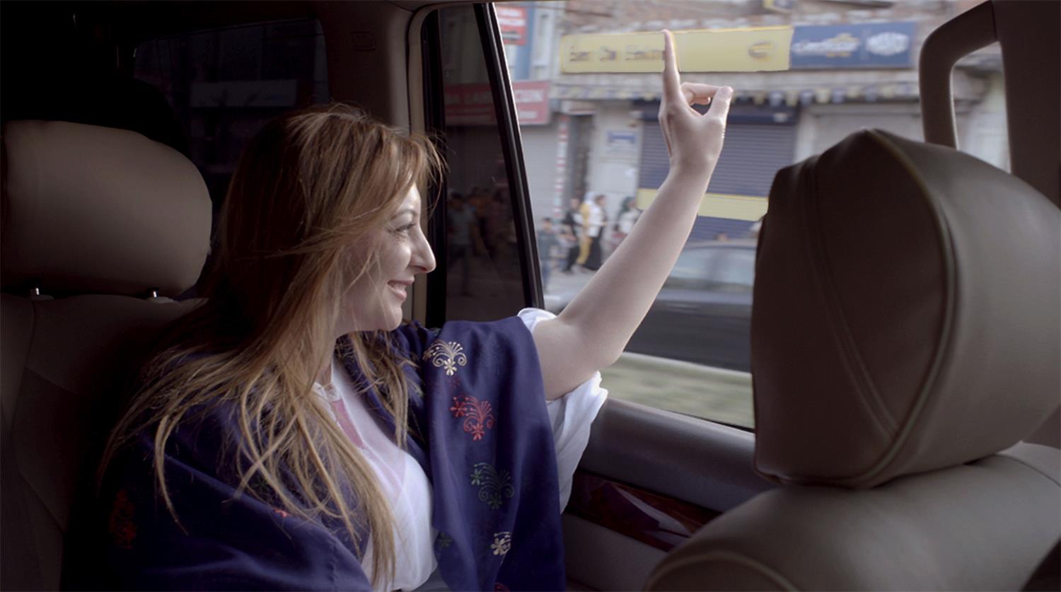 Filmszene mit Frau in einem Auto winkend