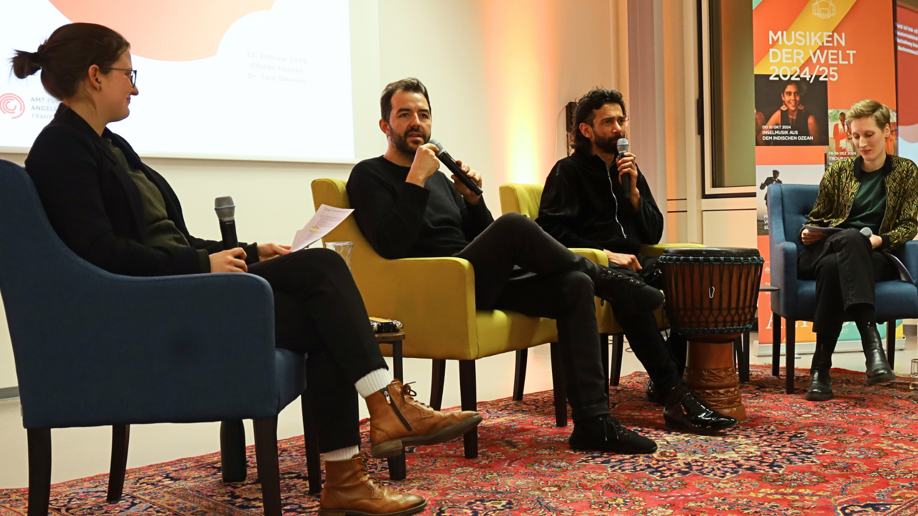 Zwei  Moderatorinnen von "Musiken der Welt" mit Gästen auf dem Podium im Gespräch