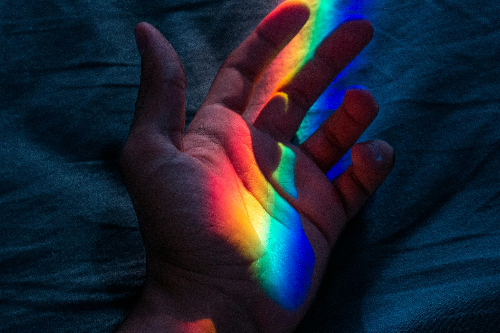 Eine Hand beleuchtet in Regenbogenfarben