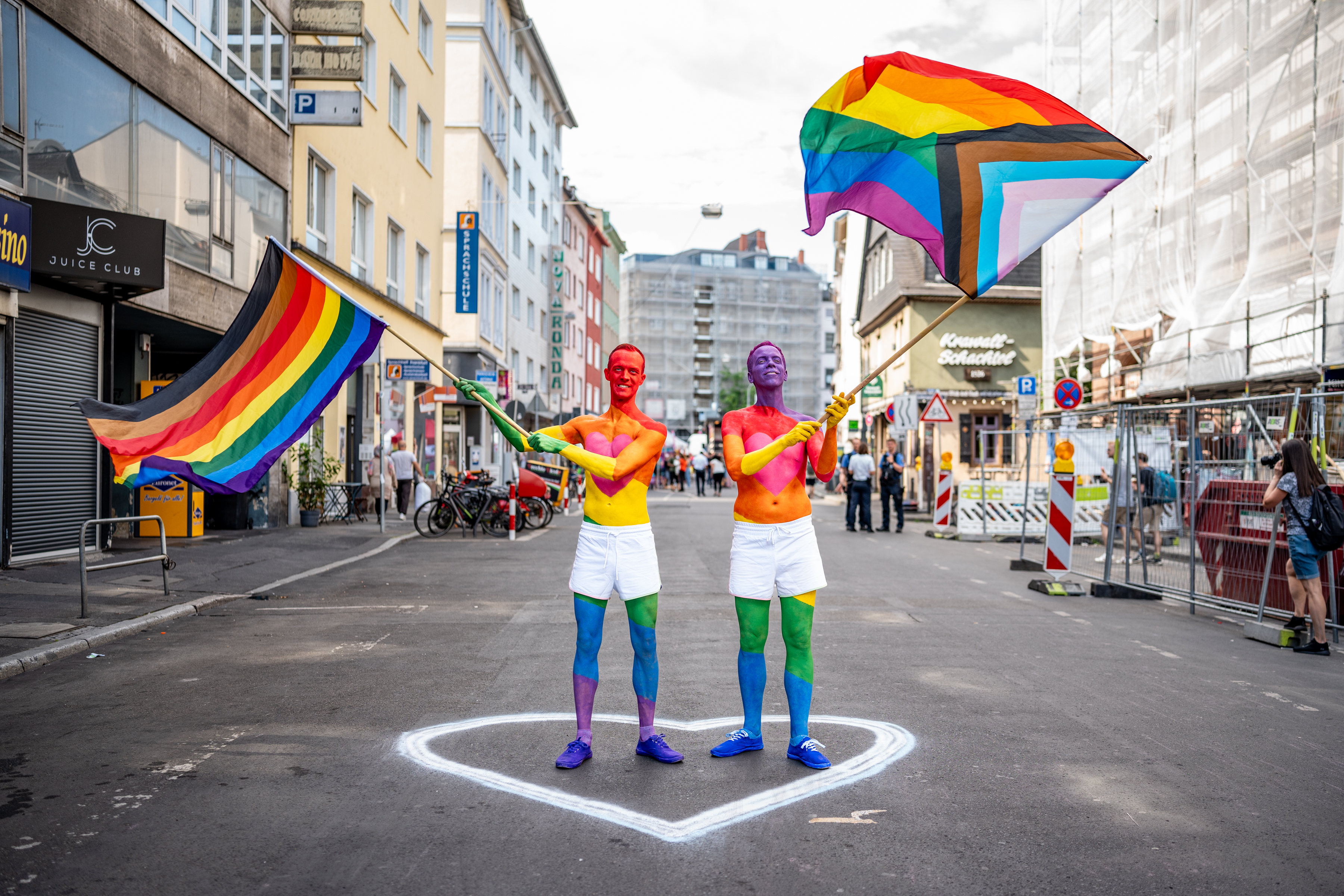 Zwei LSBTIQ-Personen mit Regenbogenfahnen