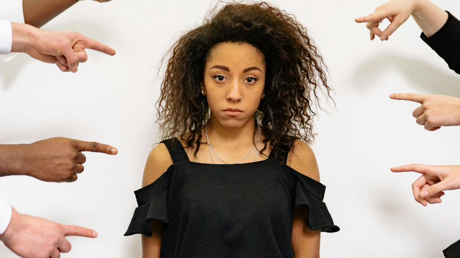 Hände, die auf eine Frau zeigen, die sich dadurch gedümütigt fühlt