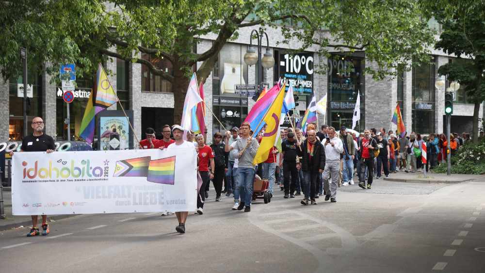 Eine Gruppe von Personen mit Regenbogenfahnen und Bannern zum IDAHOBITA* 2025 beim Marsch von der Hauptwache zum Mahnmal "Frankfurter Engel" 