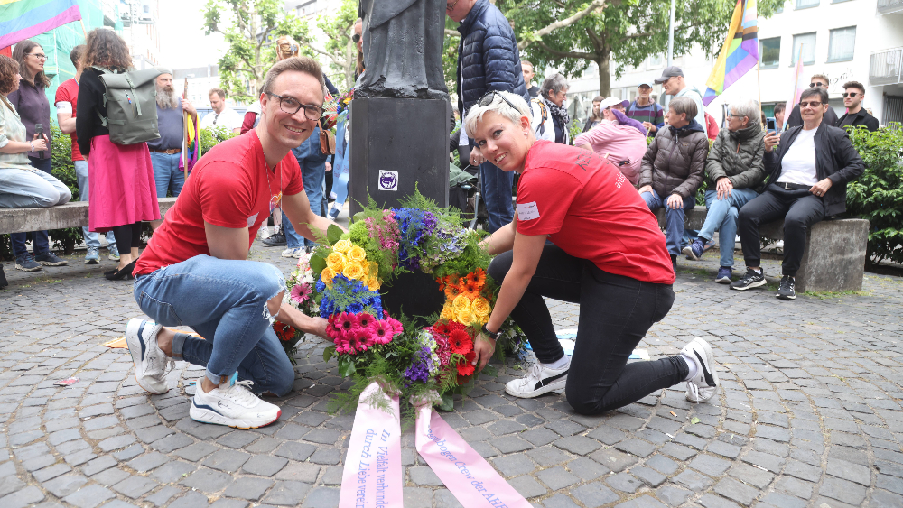 Zwei Vertreter:innen der Aidshilfe Frankfurt beim Kranz zum Gedenken vor dem Mahmal "Frankfurter Engel" nieder. 