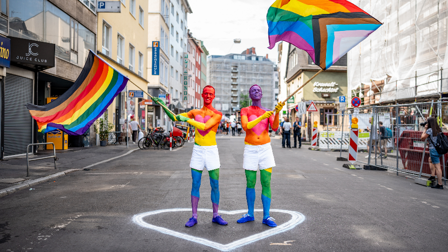 Zwei Männer mit Bodypainting und Fahnen in Regenbogenfarben