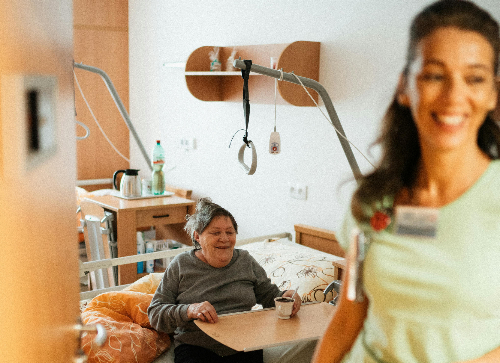 Eine Pflegerin im Zimmer einer älteren Frau