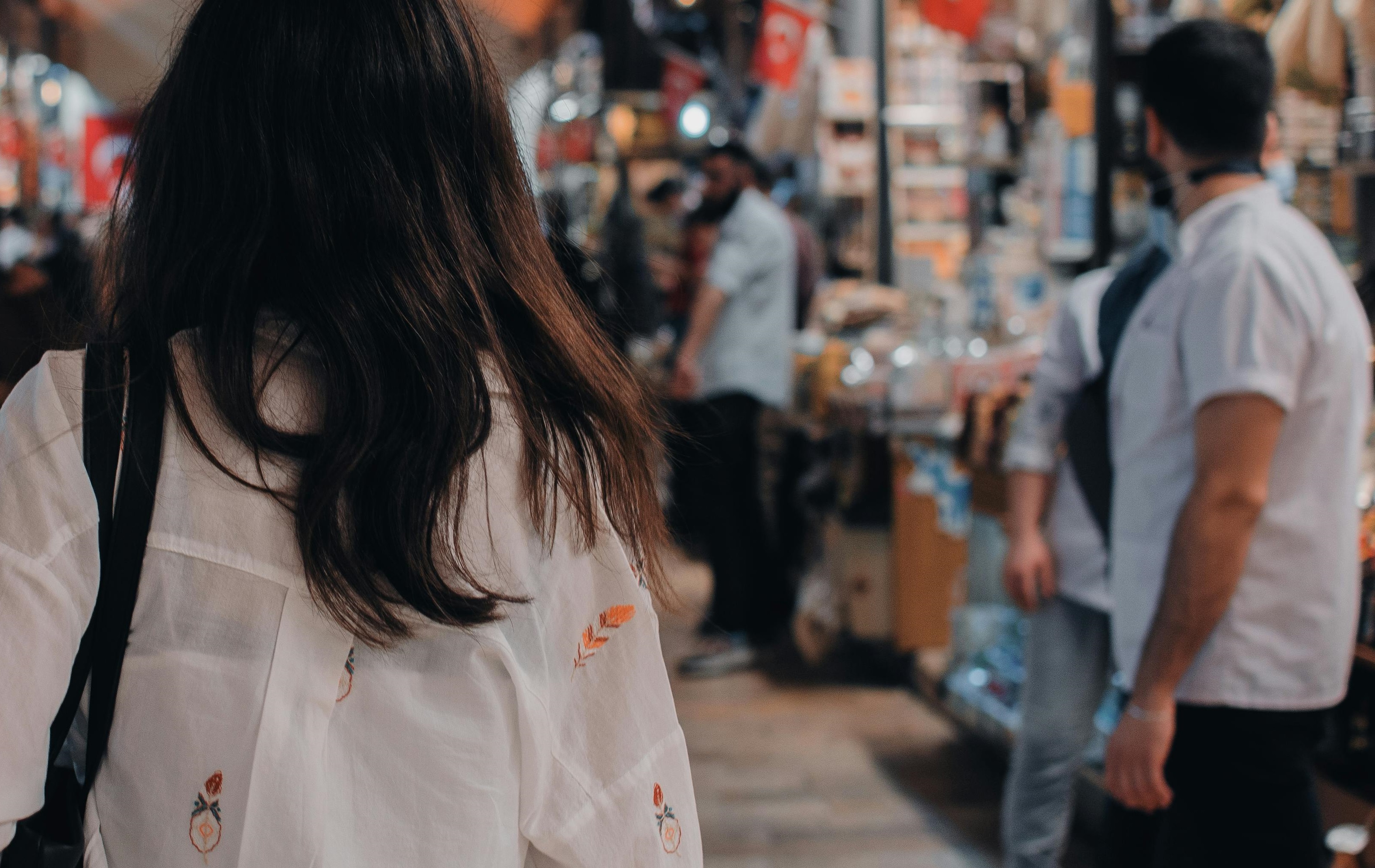 Eine Frau von hinten vor Gruppe von Menschen und Ständen