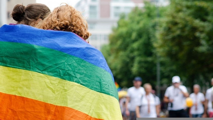 Zwei Personen eingehüllt in eine Regenbogenflagge