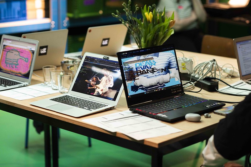 Mehrere aufgeklappte Laptops stehen auf einem Tisch. Man sieht auf den Bildschirmen Websiten mit denen Virtuelle Visuals mit Code gestaltet werden können