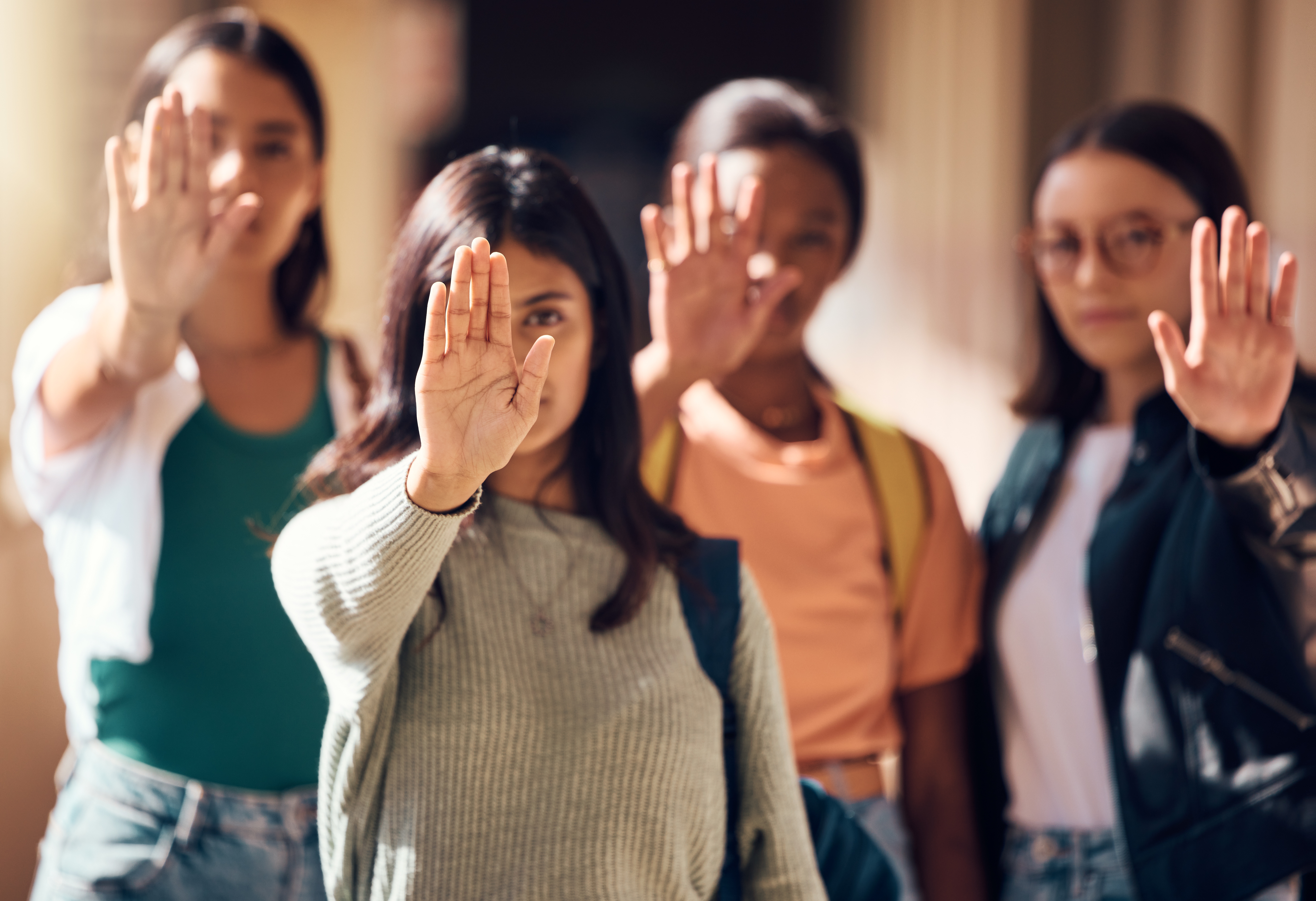 Vier weibliche junge Menschen mit erhobenen Händen protestiert mit dem Zeichen „Stopp“ für die Stärkung der Frauenrechte. Sexismus. 