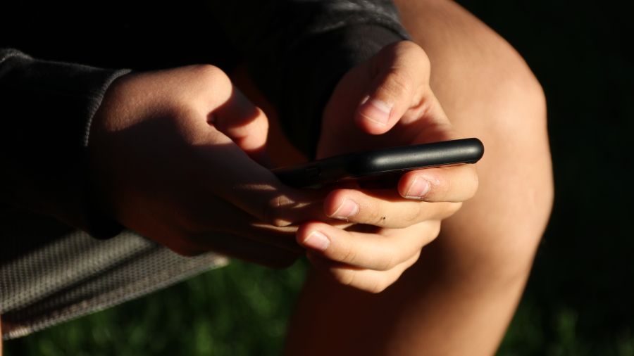 Symbolfoto mit Ausschnitt von Jugendlichem mit Handy