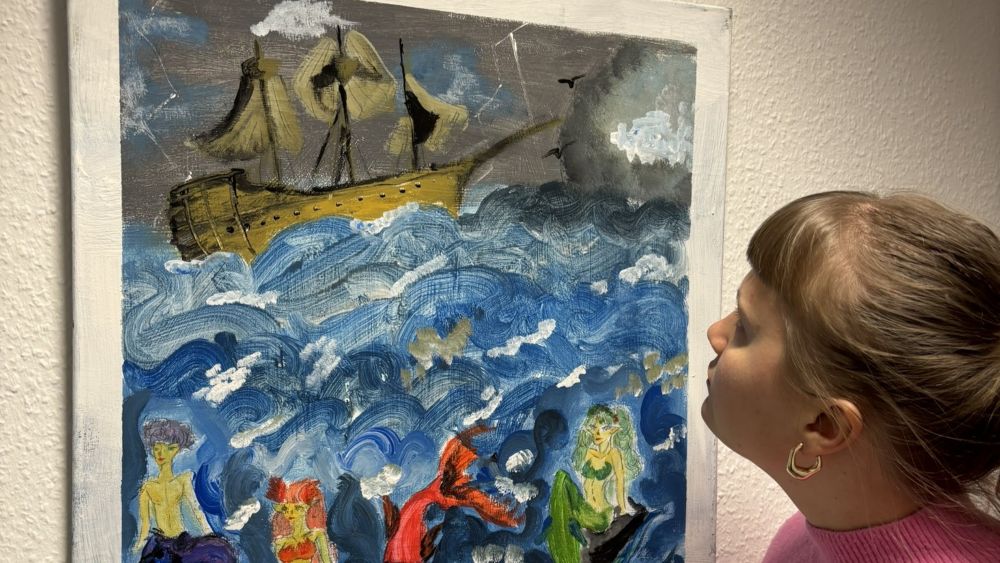 Eine Person schaut auf ein Bild, das an der Wand hängt
