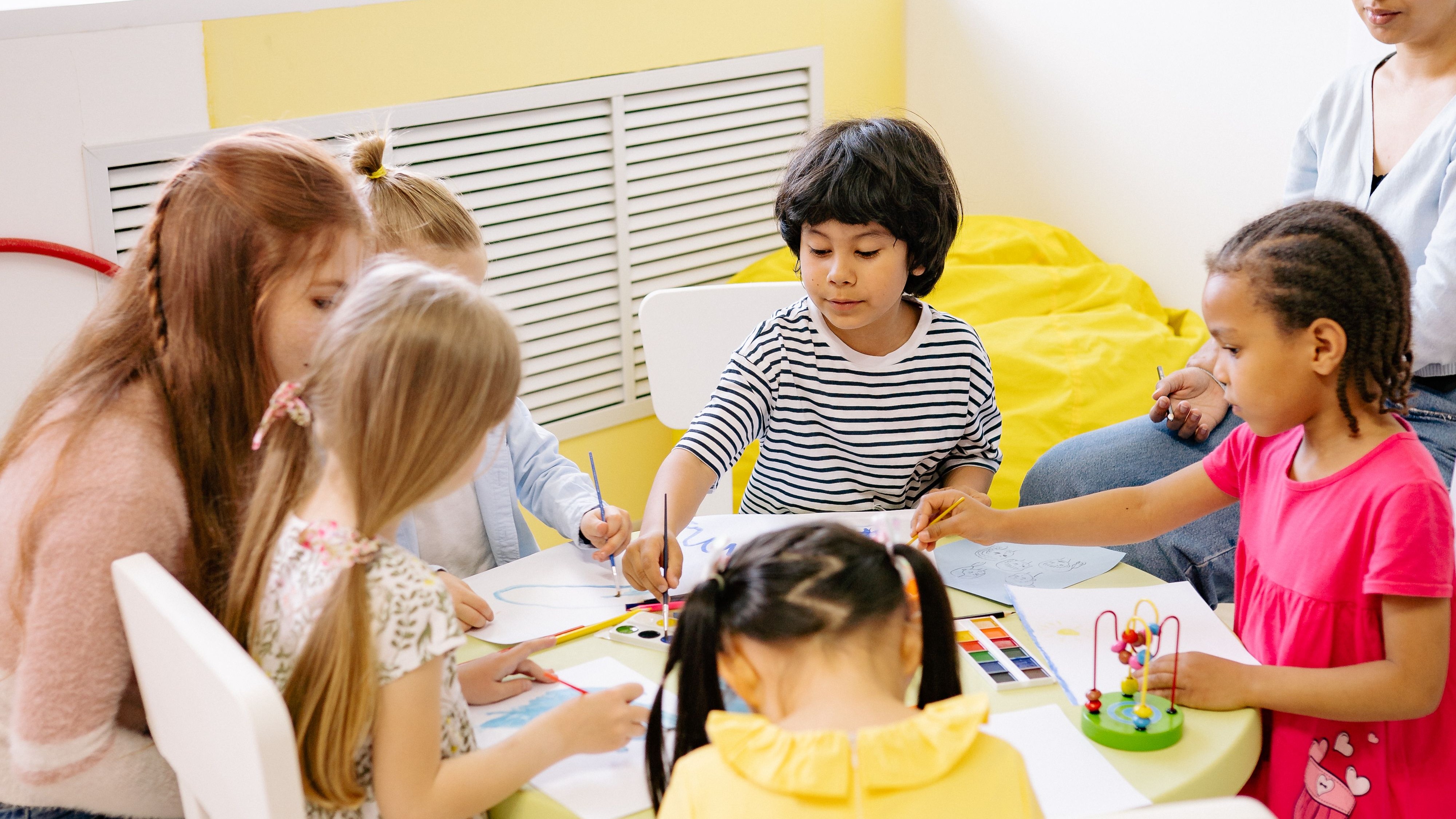 Kinder sitzen um einen Tisch herum 