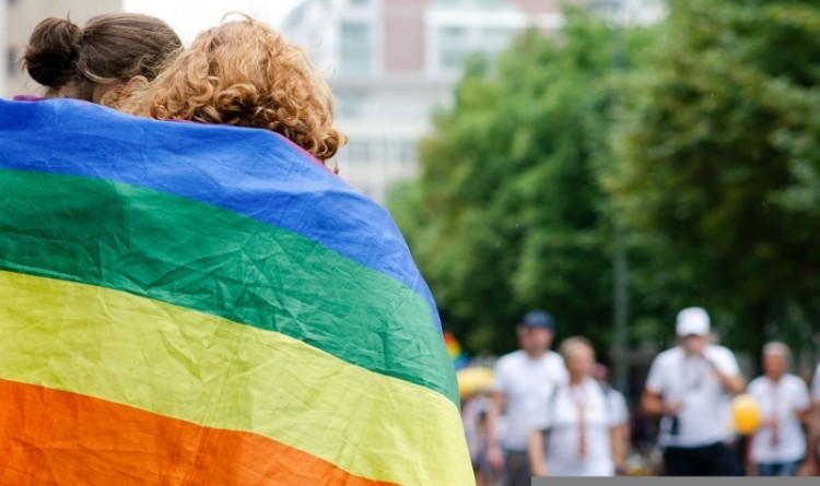 Ein Paar von hinten, gehüllt in eine Regenbogenflagge (Stadt Frankfurt)