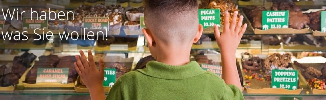  Kind von hinten vor einer Auslage in Geschäft beim Aussuchen von Süßigkeiten