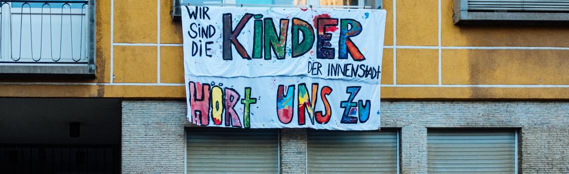 Ein Banner mit Aufschrift "Wir sind die Kinder der Innenstadt" n einer Hauswand