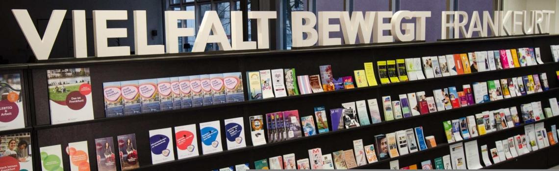 Flyerwand im Frankfurt Welcome & Information Center mit dem Schriftzug "Vielfalt bewegt Frankfurt"
